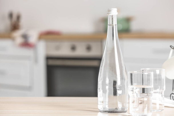 Пляшка води і окулярів на столі на кухні
 - Фото, зображення