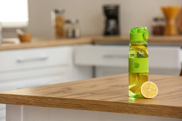 Бутылка спортивной воды с лимоном на столе на кухне - Фото, изображение