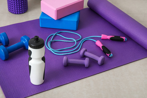 Sports water bottle with equipment on mat in gym - Foto, immagini