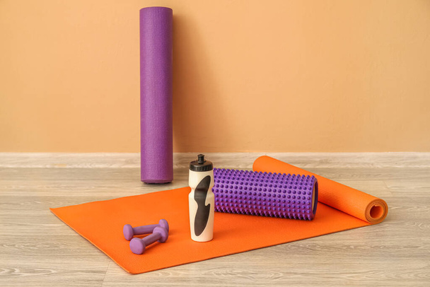 Sports water bottle with equipment on mat near beige wall - Photo, Image