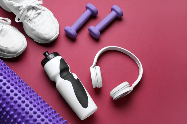 Sports water bottle with equipment, headphones and sneakers on red background - Foto, immagini