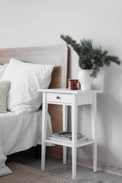 Vase with fir branches, candle and cube calendar on bedside table in room - Photo, image