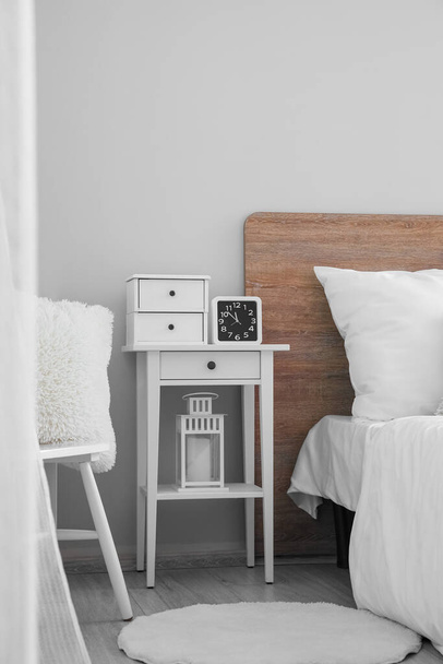 Bedside table with drawers and alarm clock in light bedroom - Zdjęcie, obraz