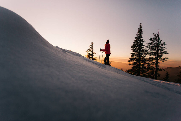 Retkeilijä nainen kävelysauvat nauttia majesteettinen auringonlasku talvella Hasmas vuoristossa, Transilvania, Romania. Ulkona, Seikkailu käsite - Valokuva, kuva