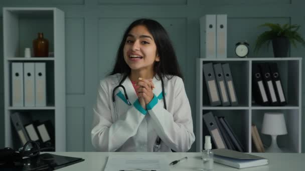Happy young woman doctor medic looking at camera use virtual video connection consulting patient online share news congratulating good health test results give support clapping hands ovation gesture - Felvétel, videó