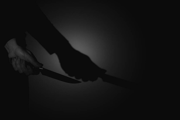 A woman's hand holds a knife in the dark, violence, danger, weapons, harm - Photo, Image