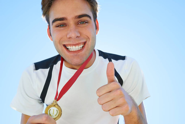 Гордий спортивний момент. Усміхнений переможець медалі жестикулює великими пальцями вгору з посмішкою
 - Фото, зображення