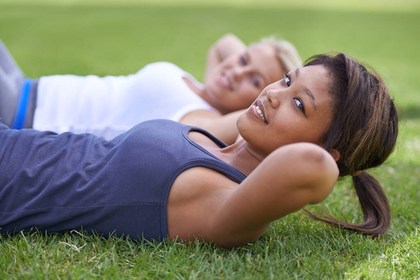 Gettung an ab workout. young women doing sit ups on the grass outside - Foto, Imagem