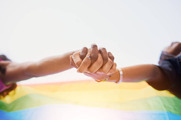 LGBTQ flag, rainbow and couple holding hands for gay pride, lesbian support or human rights protest. LGBT community, sky and African black people together in love, partnership and equality below view. - Foto, immagini