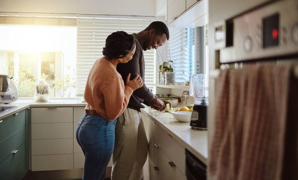 Black couple, cooking and helping with food in kitchen at home while together to cook healthy food. Happy young man and woman in their house or apartment to bond and prepare lunch or dinner with love. - Foto, Imagem