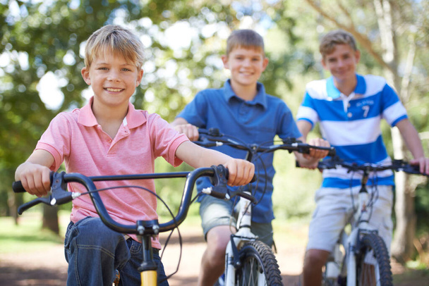 Весёлый способ тренироваться. Портрет трех молодых братьев, едущих на велосипедах снаружи - Фото, изображение