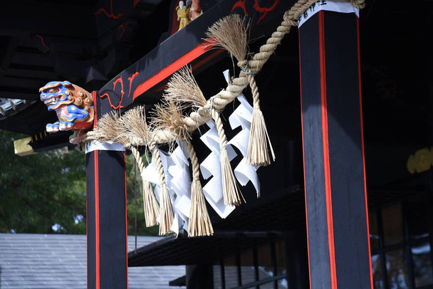 'Shimenawa' ( Shinto straw festoon ) in the japanese shrine. Shimenawa consists of a rice-straw rope and white paper cut in stripes. It is considered a barrier against evil spirits. - Foto, Bild