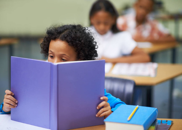 Хит книги. Этнический мальчик, читающий в книге в классе - Фото, изображение
