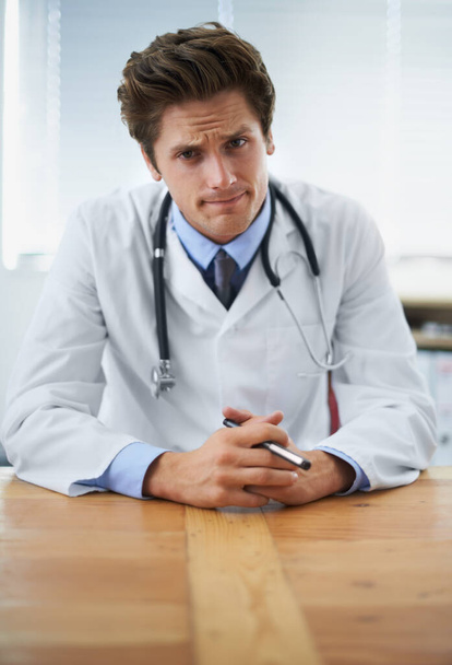 Your progress isnt as good as we hoped...Portrait of a serious young doctor sitting at his desk - Foto, Bild