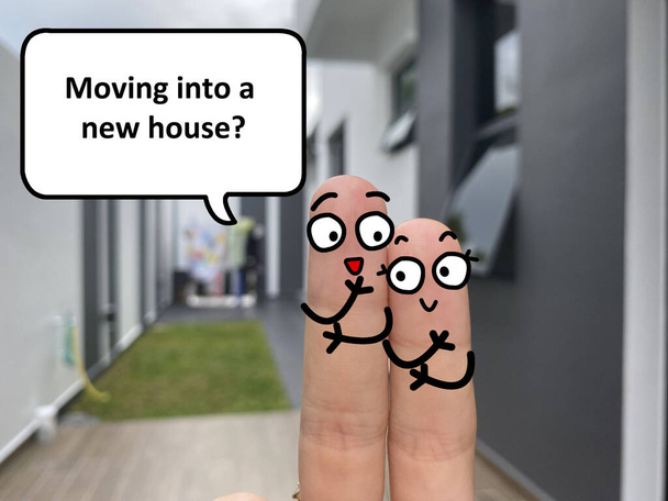 Δύο δάχτυλα είναι διακοσμημένα ως δύο άτομα που στέκονται έξω από ένα νέο σπίτι. Η μία ρωτάει την άλλη αν μετακομίζει σε νέο σπίτι.. - Φωτογραφία, εικόνα