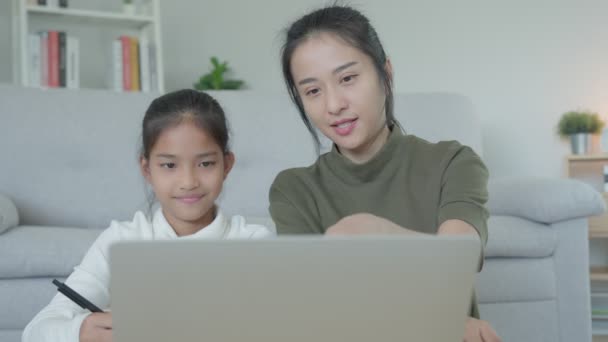 Anya leckét ad a lányának laptoppal. Ázsiai fiatal lány tanul otthon. Csináld meg a leckédet kedves anyai segítséggel, bátorítsd a vizsgára. Ázsiai lány boldog magániskolát. Anya tanácsolja az oktatást. - Felvétel, videó