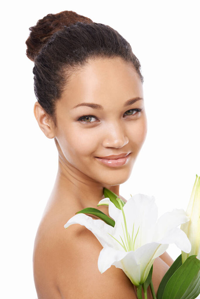 It mimics her beauty. A beautiful young woman holding a lilly against a white background - Photo, image