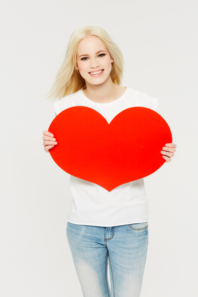 Red heart, love and portrait of woman in studio for peace, self love and affection on white background. Shape, emoji and face of girl holding cardboard sign, loving and gesture with mockup space. - Foto, Imagem