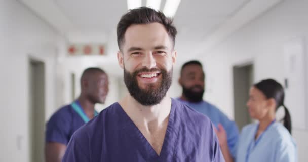 Video portrait of smiling, bearded caucasian male medical worker in busy hospital corridor. Hospital, medical and healthcare services. - Filmmaterial, Video