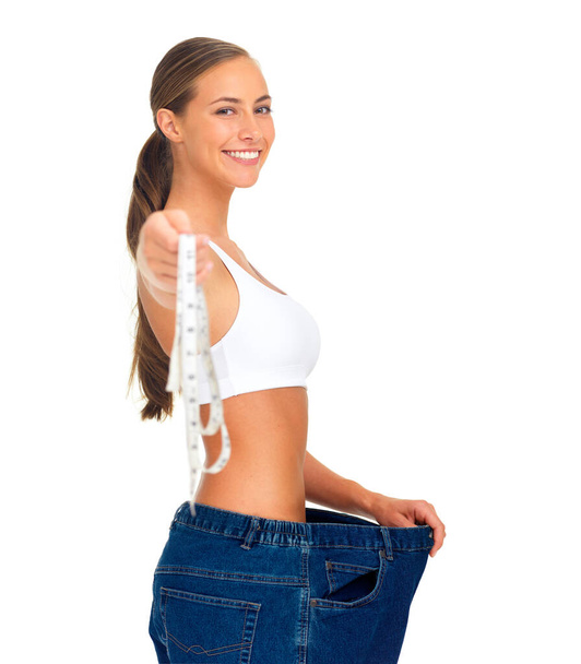 Diet, weightloss and happy woman with measuring tape, jeans and smile isolated on white background. Fitness, healthcare and wellness, woman with slim figure and liposuction skinny waist measurement - Photo, image