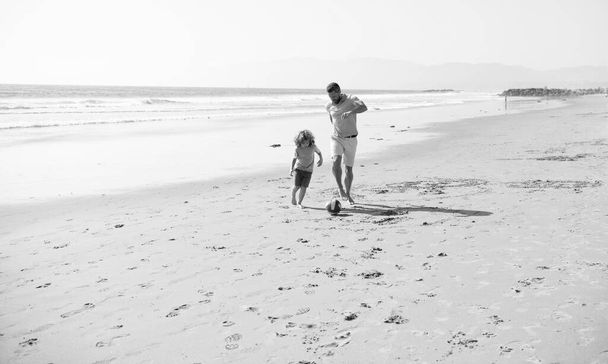 Apa kisfiúval a nyári napon. Hétvégi családi nap. Apa és a gyerek jól érzik magukat a szabadban. gyermekkor és nevelés. Családi nyaralás. sport tevékenység. apa és fia focizni vagy focizni a strandon. - Fotó, kép