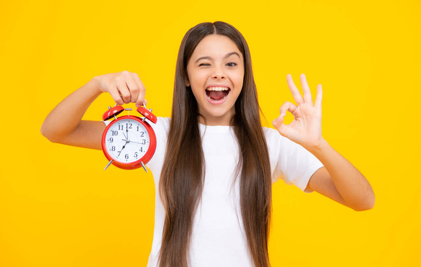 Punctual teen girl checking time. Child with alarm clock showing time. Excited teenager, glad amazed and overjoyed emotions - Zdjęcie, obraz