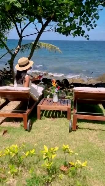 Asian women drinking wine at the oceanfront with a look over the tropical sea of Koh mak Thailand.  - Filmati, video