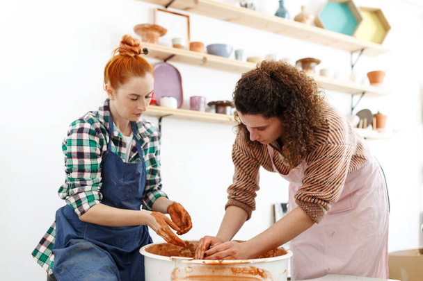Женщина-производитель керамики, работающая с гончарным колесом в уютном мастерской делает будущую вазу или кружку, творческие люди ручной керамики класса. - Фото, изображение