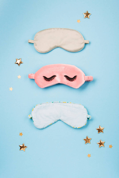 World Sleep day observed on March. Quality of sleep, good night, insomnia, relaxation concept. Sleeping masks, golden stars and white alarm clock on blue background. Flat lay, top view - Fotó, kép