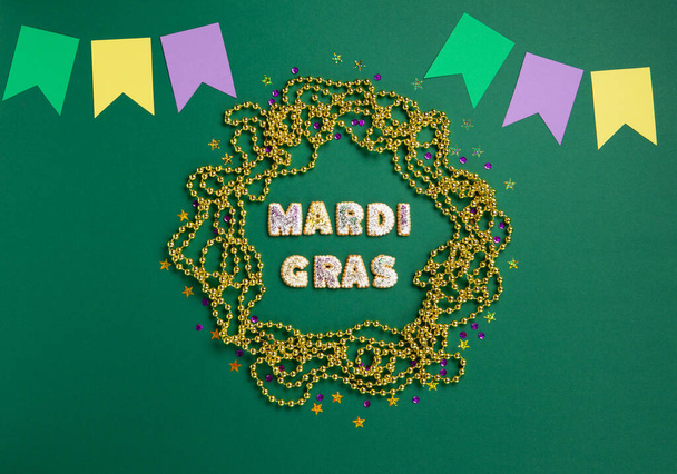 Mardi Gras King Cake ccookies, masquerade festival carnival mask, gold beads and golden, green, purple confetti on green background. Holiday party invitation, greeting card concept. - Fotografie, Obrázek