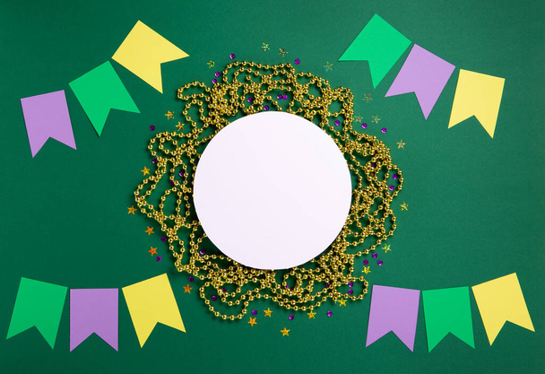 Mardi Gras masquerade festival carnival mask, gold beads and golden, green, purple confetti on green background. Holiday party invitation, greeting card concept. Top view, copy space. - Fotografie, Obrázek