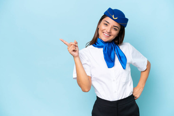 Airplane stewardess caucasian woman isolated on blue background pointing finger to the side - Foto, Imagem