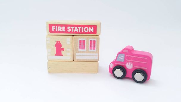 Close up of wooden fire station and wooden fire truck on white background. Wooden toys. - Foto, Bild