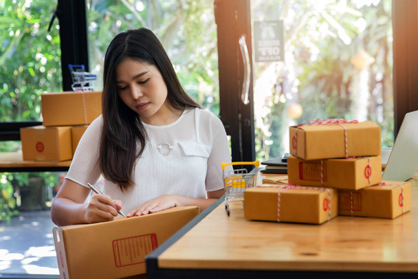Úspěšná podnikatel obchodní žena s on-line prodej a balíkové dopravy ve své domovské kanceláři, připravit balíček zboží pro dodání zákazníkovi. - Fotografie, Obrázek