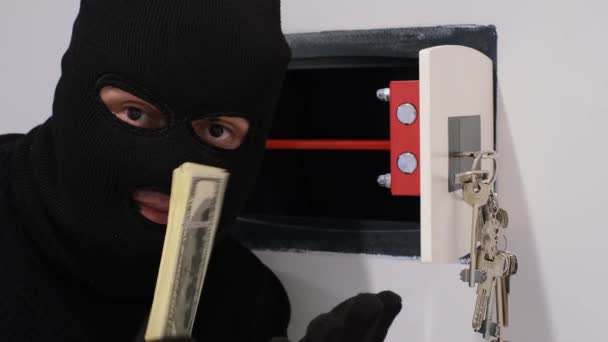 A robber in a black mask opens the safe and steals money. Apartment thief. Hacking the safe. 4k video - Felvétel, videó