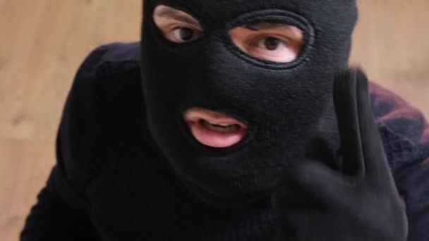 An unidentified person threatens the surveillance camera. A man in a balaclava. Aggressive robber - Materiał filmowy, wideo