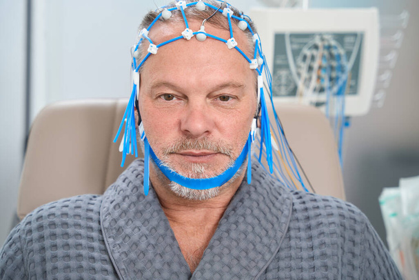 Patient has a grid of electrodes for encephalography on his head, he is undergoing a check-up at the medical center - Fotoğraf, Görsel