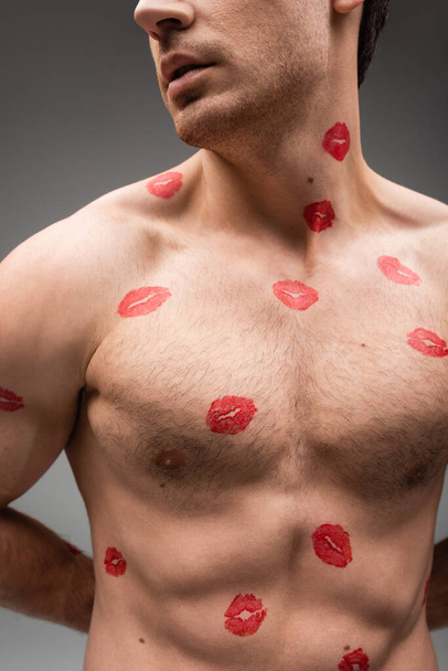 partial view of sexy shirtless man with red lipstick marks on muscular body isolated on grey - Photo, Image