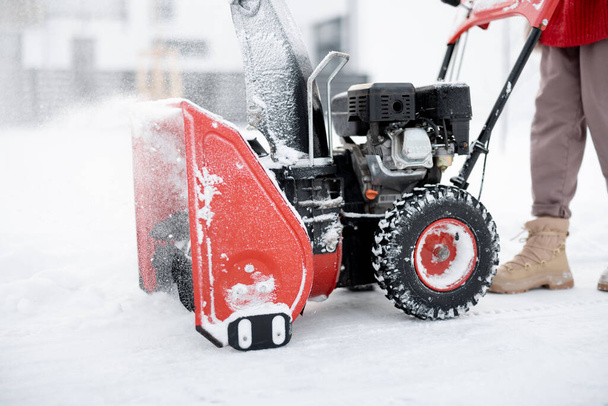 Osoba tlačí stroj na vrhání sněhu, čistí cestu ze sněhu, detailní záběr na stroj, který odfoukne sníh - Fotografie, Obrázek