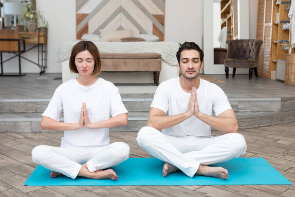 Young couple doing yoga together at home. Family doing sport together concept - Foto, Imagem