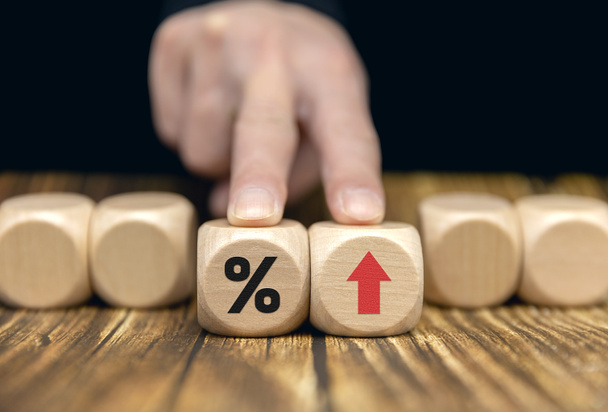The entrepreneur is holding a block of wood with a percentage and an up arrow. a mortgage rate Interest rates, stocks, rankings, business and financial concepts. - Photo, Image