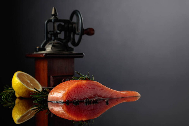 Salmon with rosemary, lemon, and peppercorn on a dark background. Copy space. - Foto, immagini