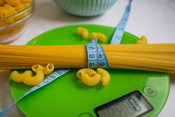 Dry pasta, kitchen scales on a light background - Fotó, kép