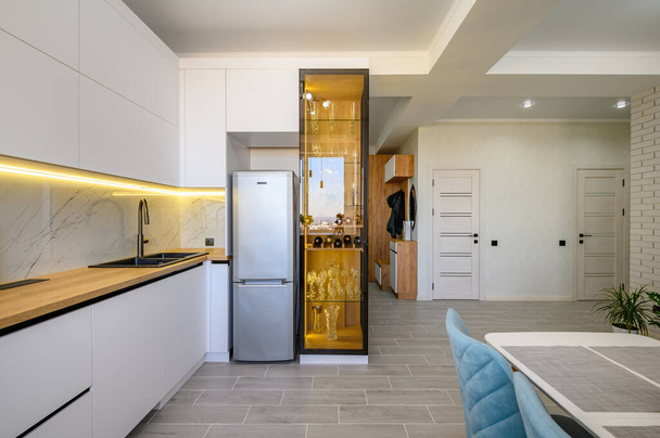 Een moderne witte studio met een volledig uitgeruste keuken die klaar is voor gebruik - Foto, afbeelding
