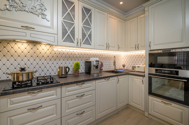 Cocina clásica de color beige con amplio espacio de mostrador y una variedad de electrodomésticos - Foto, Imagen