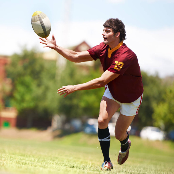 My passion. Full length shot of a young rugby player receiving a pass - Foto, immagini