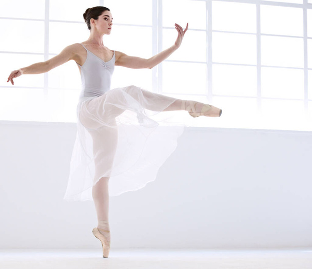 Control and perfection. Graceful young ballerina in white dancing en pointe - Fotoğraf, Görsel