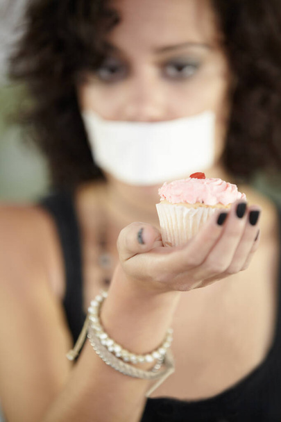 Mondj nemet a cukorra. Egy fiatal nő süteményt tart a szájával. - Fotó, kép