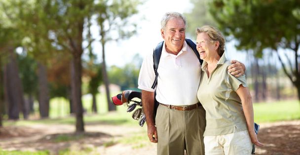 Наслаждаюсь их днем гольфа вместе. Портрет пожилой пары, смеющейся и улыбающейся во время игры в гольф - Фото, изображение