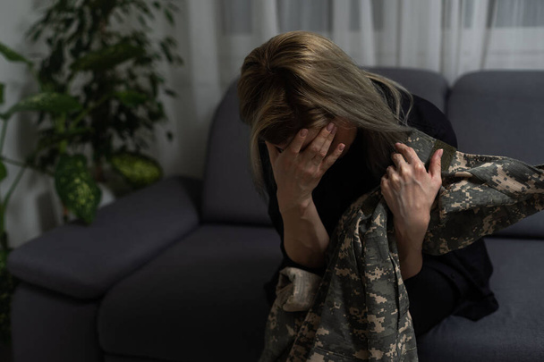 Vista ritagliata di donna che detiene abbigliamento militare a casa
 - Foto, immagini